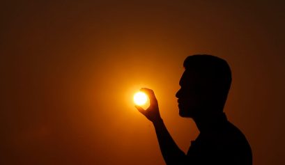 Persona tocca con le mani il sole al tramonto -Earth Hour AERA